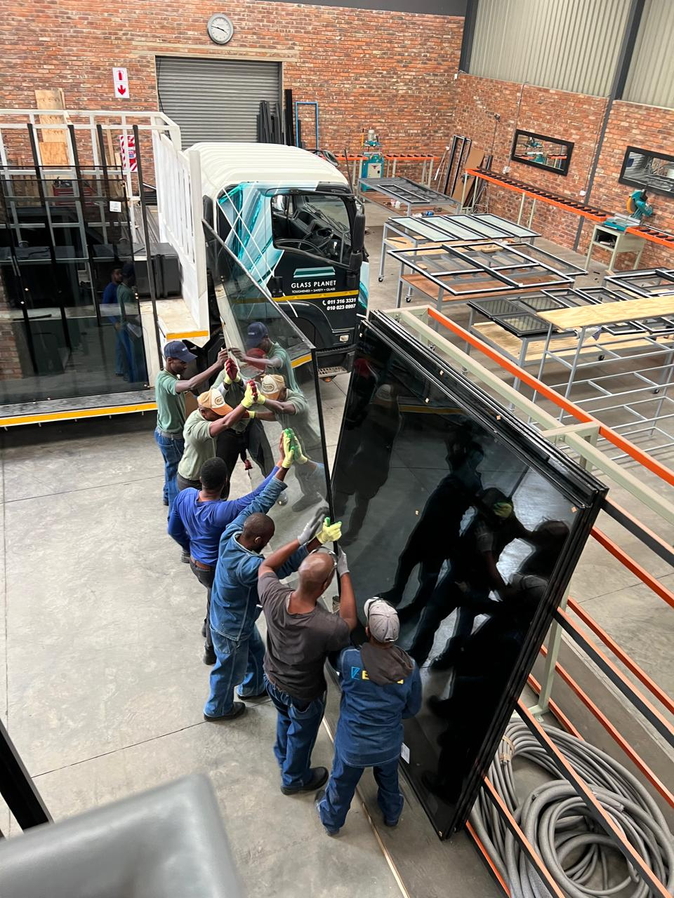 EverAlu team carefully handling a large glass panel in the workshop