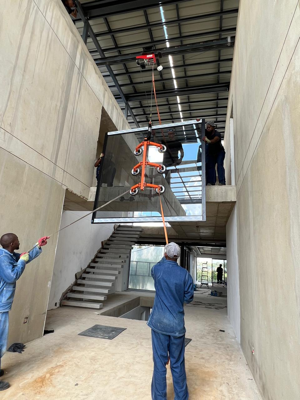 EverAlu installers hoisting a large glazed unit on a residential site